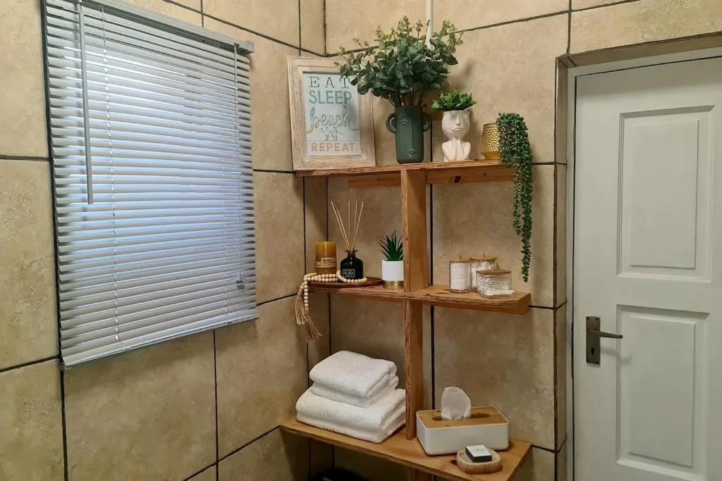 Wooden shelving unit with plants, towels, and decorative items in bathroom