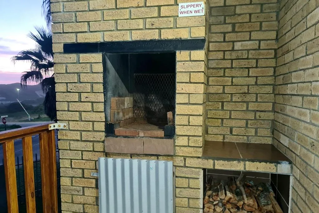 Outdoor braai fireplace with brick construction and firewood storage below