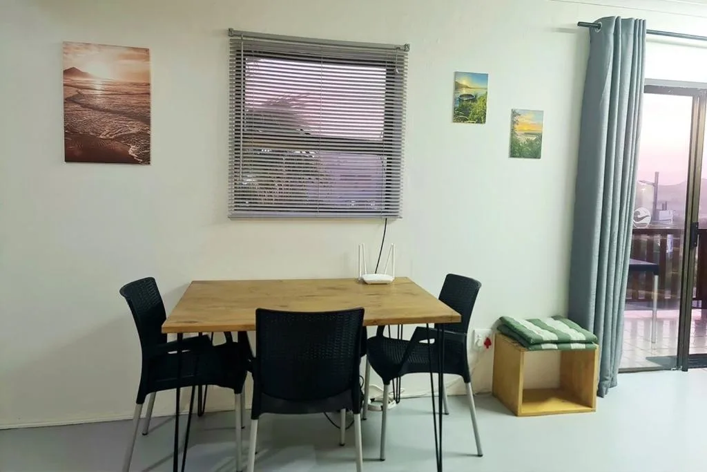 Wooden dining table with black chairs in bright, naturally lit room