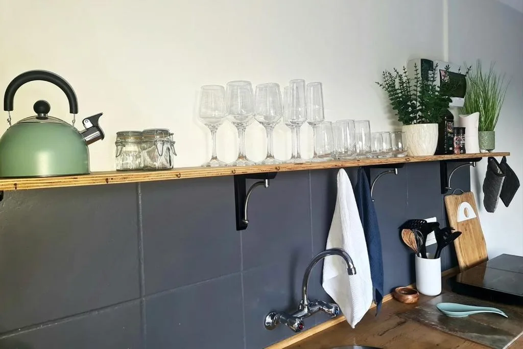 Modern kitchen shelving with glasses, kettle, plants, and utensil storage
