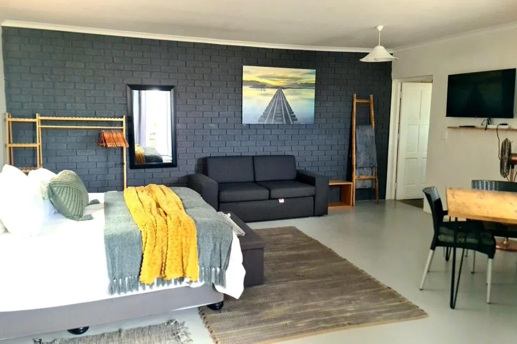 Open-plan studio with bed, black sofa, and dining area visible