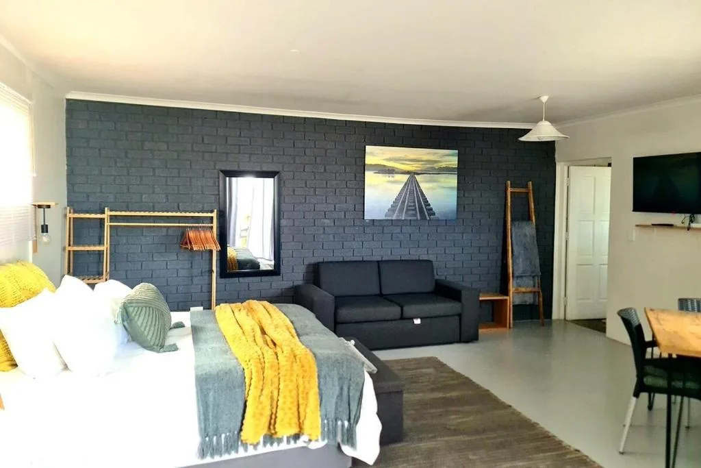 Modern studio lounge with black sofa, bed, and dark feature wall