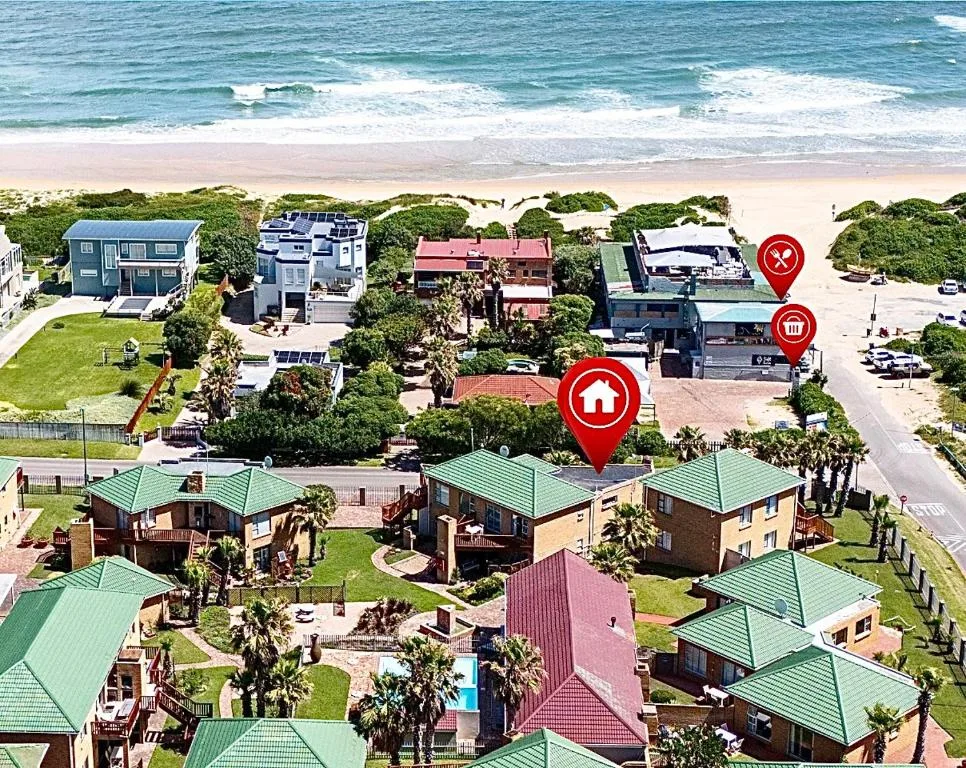 Aerial view of beachfront property complex with ocean and sandy beach beyond