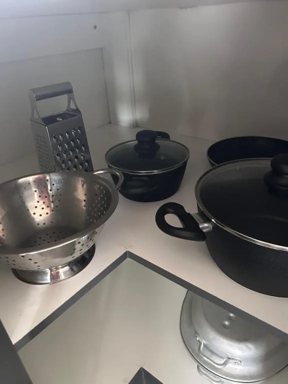 Kitchen cookware including grater, pots, and colander on counter