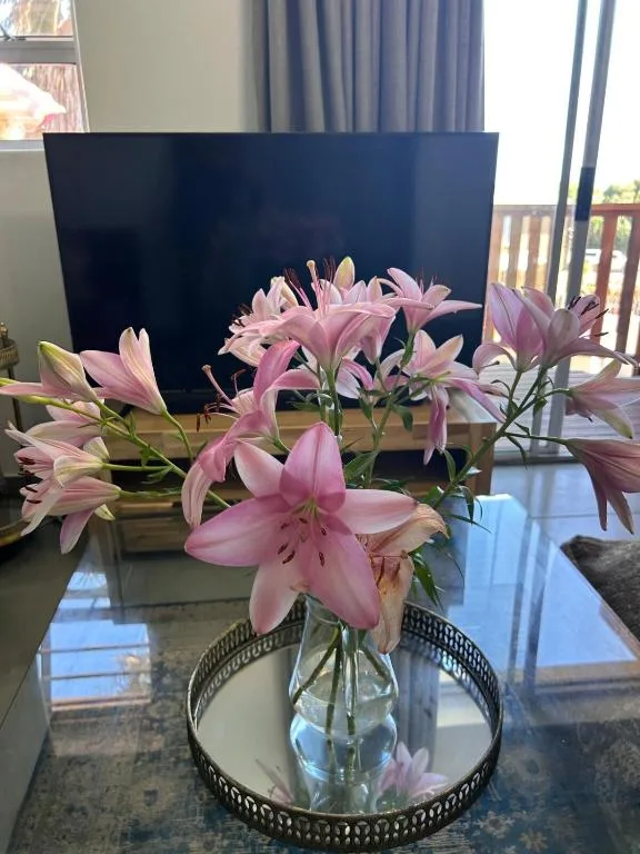Pink lilies in glass vase on decorative tray, lounge setting