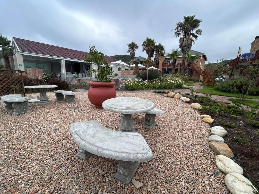 Spacious garden courtyard with stone tables, red pot feature, and palm trees