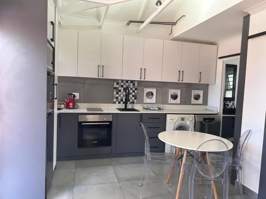 Modern kitchen with white upper cabinets, dark lower units, and integrated appliances