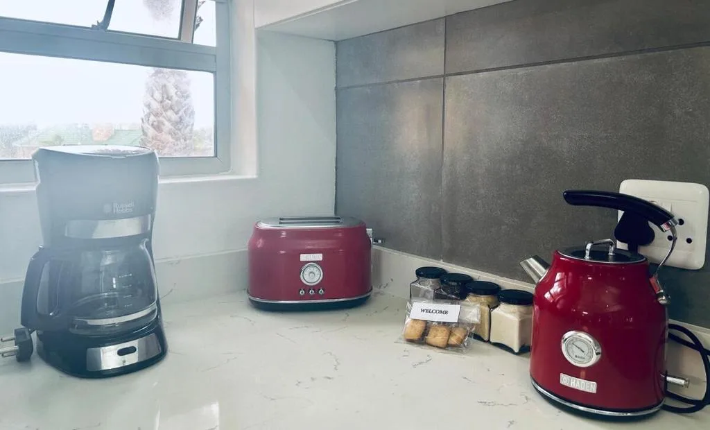Modern kitchen counter with red appliances and coffee maker