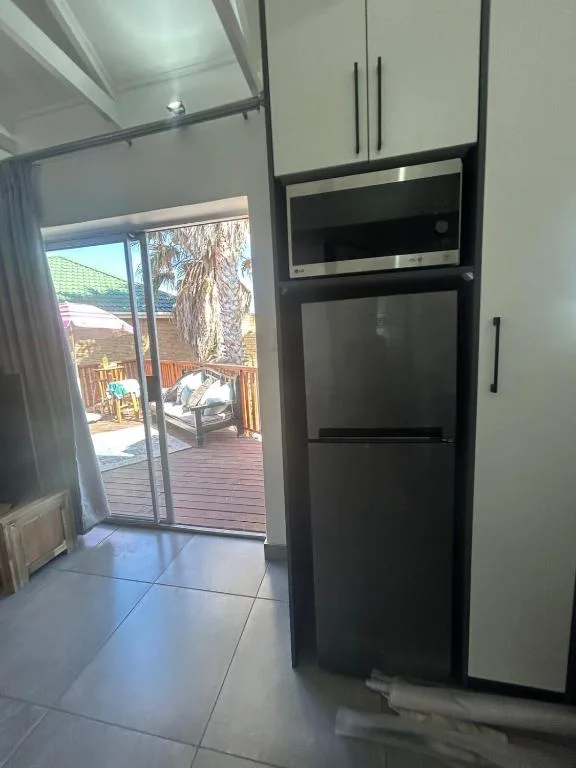Modern kitchen with black appliances and open door to wooden deck