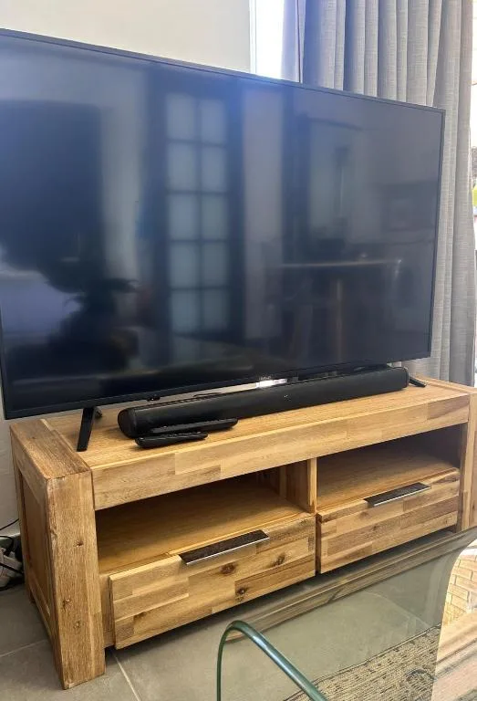 Flat-screen TV mounted on wooden entertainment unit with storage