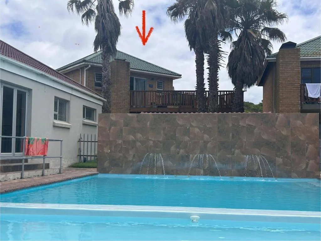Bright blue swimming pool with decorative water fountains and brick wall backdrop