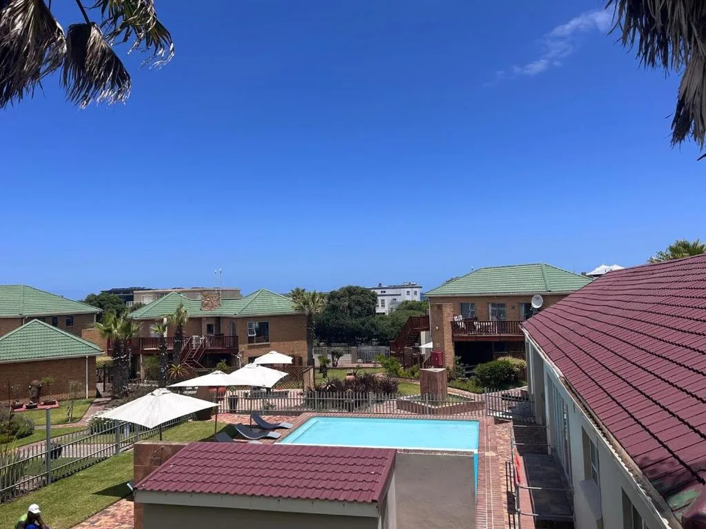 Rectangular swimming pool surrounded by brick buildings with colorful roofs