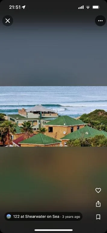 Coastal property with ocean waves and beach landscape beyond green lawns