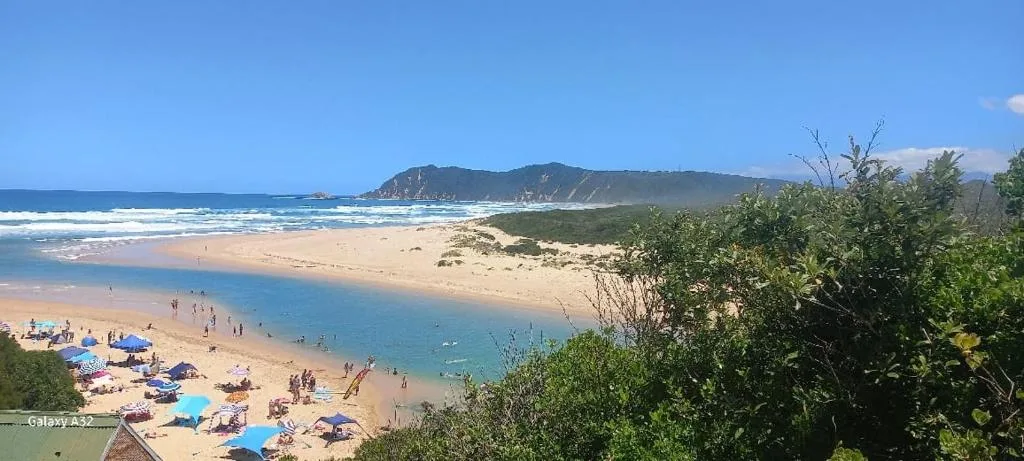 Panoramic beach view with lagoon, mountains, and beachgoers enjoying the water