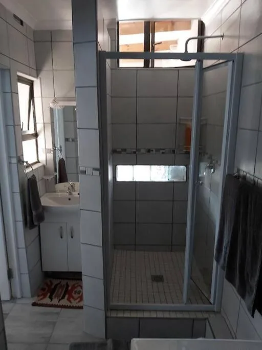 Modern walk-in shower with glass enclosure and white tiled walls