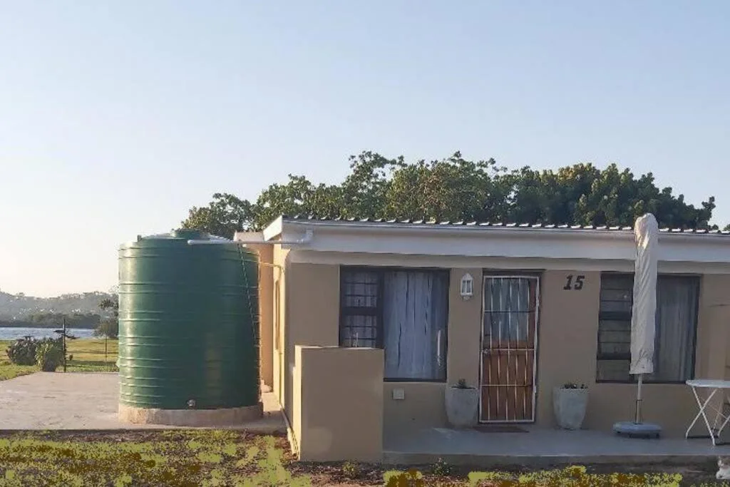 Tan cottage with green water tank and blue door entrance