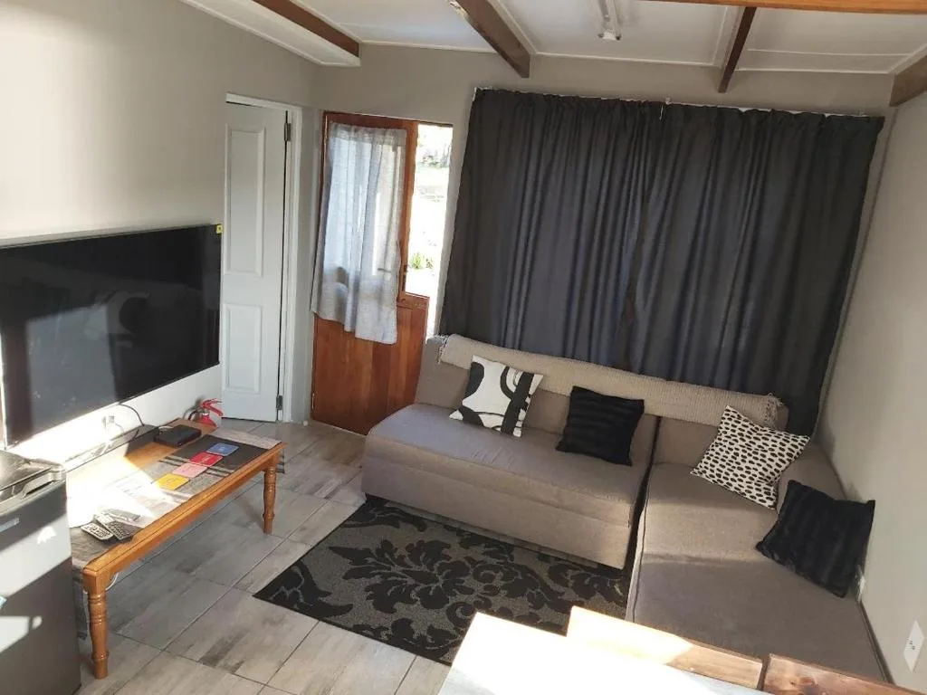 Open-plan lounge with beige sofa, fireplace, and dark curtained windows