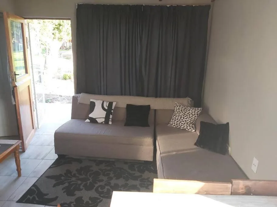 Modern lounge with beige L-shaped sofa and patterned rug, opening to patio