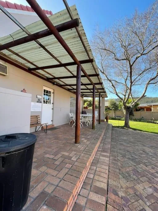 Covered patio area with pergola, brick flooring, and garden views