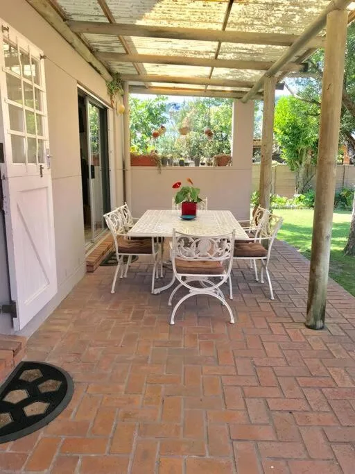 Covered patio with dining table and chairs overlooking garden