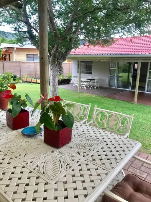 Patterned patio with potted plants, chairs, and manicured lawn beyond