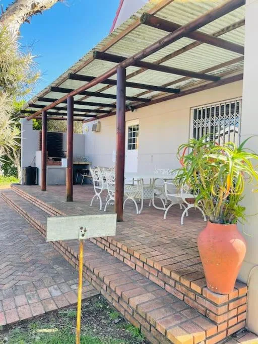 Covered pergola patio with white chairs and potted plants