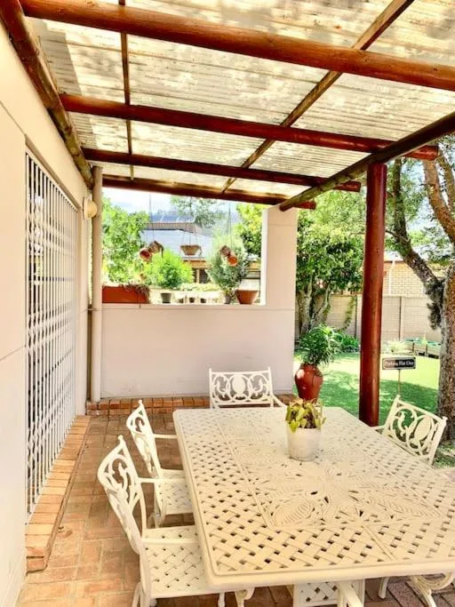 Covered patio with wooden pergola, dining table, and garden views