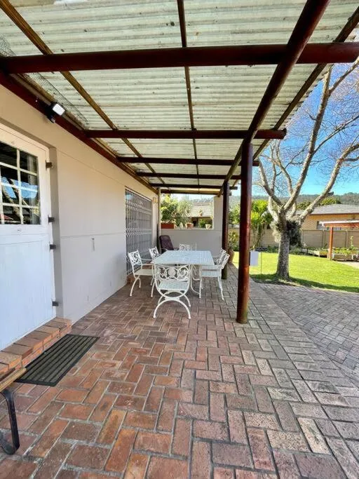 Covered patio with dining table, brick floors, and garden views