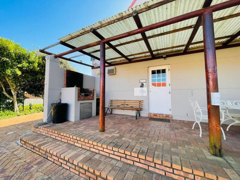 Covered patio with brick flooring, wooden pergola, and outdoor seating