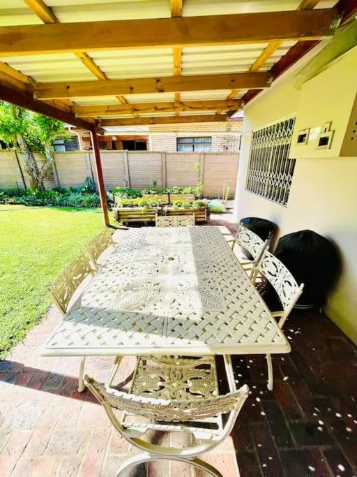 Covered patio with dining table and chairs overlooking green garden