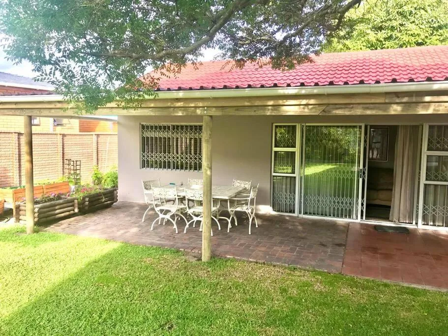 Covered patio with dining tables and chairs, brick flooring, garden view