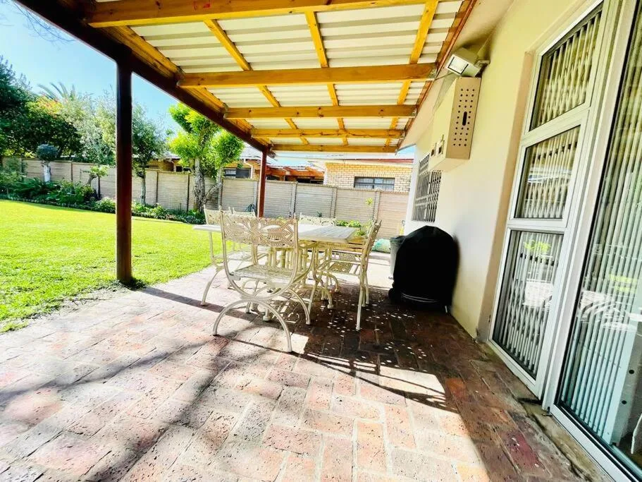 Covered patio with wooden pergola, seating area, and views of manicured garden