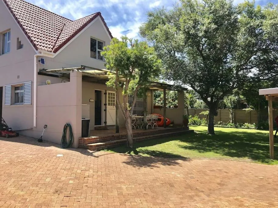 Pink cottage with red-tiled roof, brick patio, garden, and covered porch area