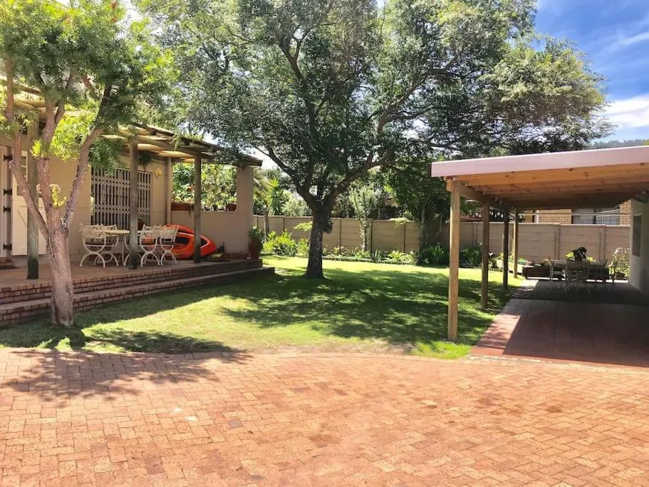 Spacious garden courtyard with mature trees, brick paving, and covered deck areas