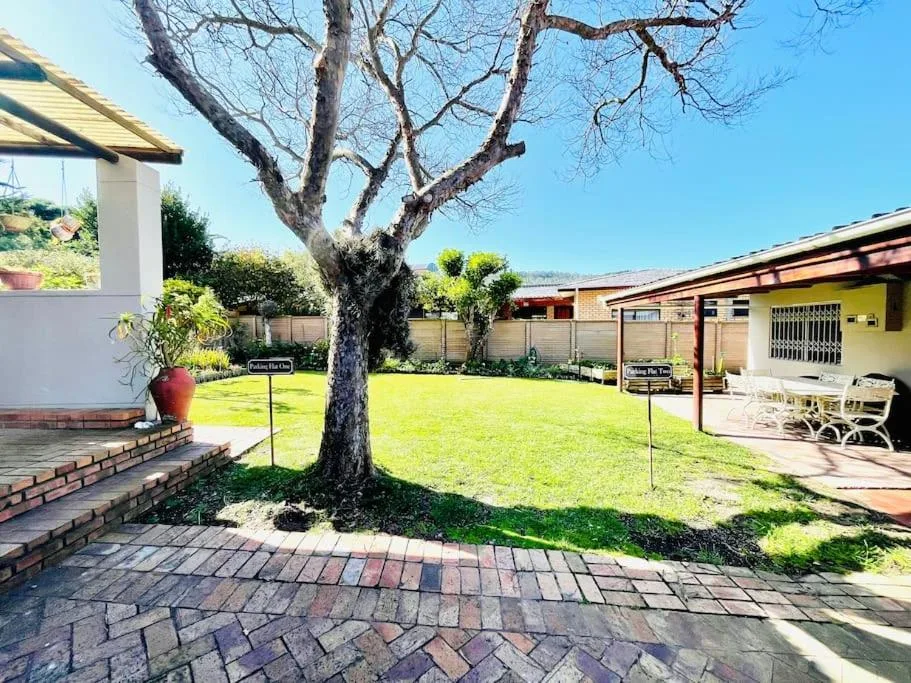 Spacious garden with mature tree, brick paving, and cottage buildings