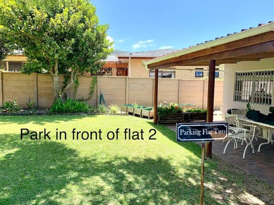 Brick cottage exterior with manicured lawn, wooden pergola, and parking area