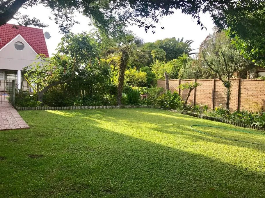 Lush green garden with manicured lawn, mature trees, and brick cottage entrance