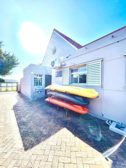 White cottage exterior with colorful kayaks leaned against building wall