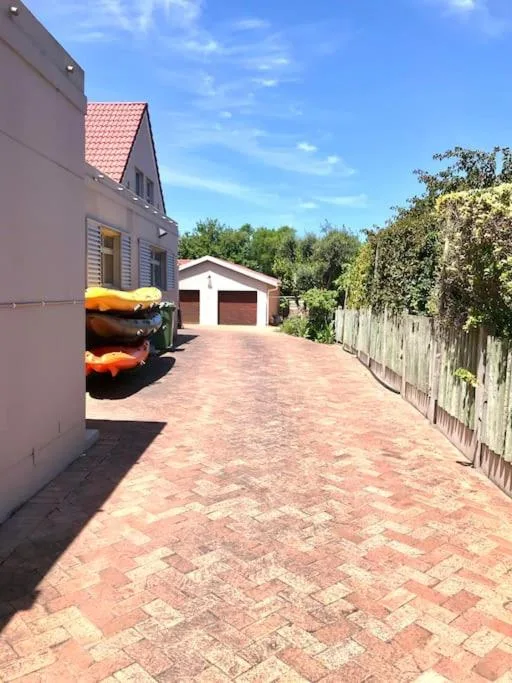 Brick driveway with property entrance, garage, and garden surroundings