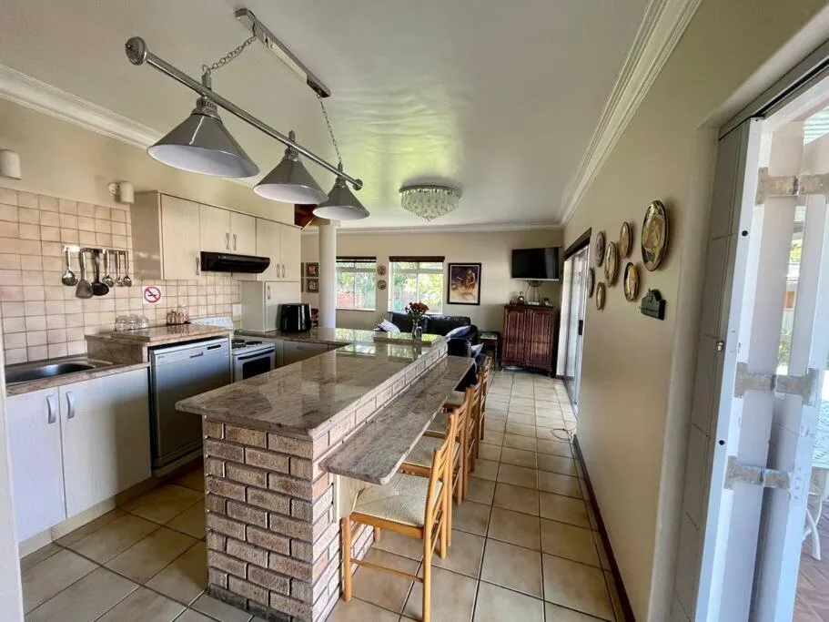 Open-plan kitchen with island bench, cream cabinetry, and dining area beyond