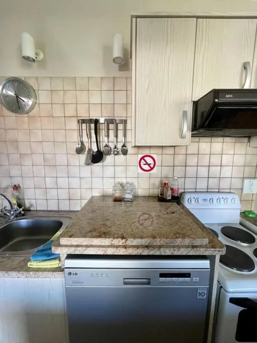 Kitchen with granite countertop, dishwasher, sink, and tiled backsplash