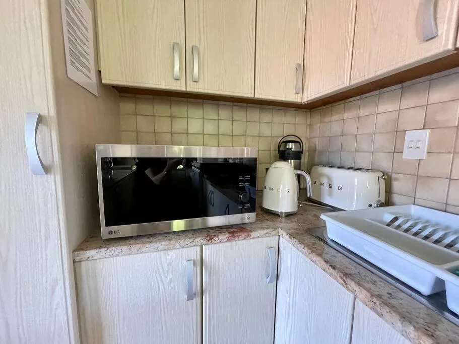 Compact kitchen with microwave, kettle, toaster, and countertop appliances