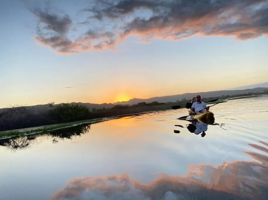 Sunset over lagoon with mountains and kayaker in distance