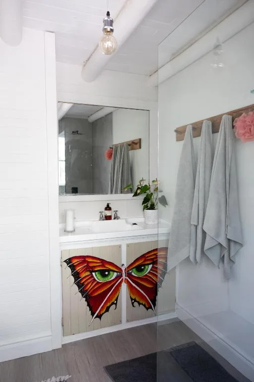 Modern bathroom with vanity sink, large mirror, and artistic butterfly cabinet doors