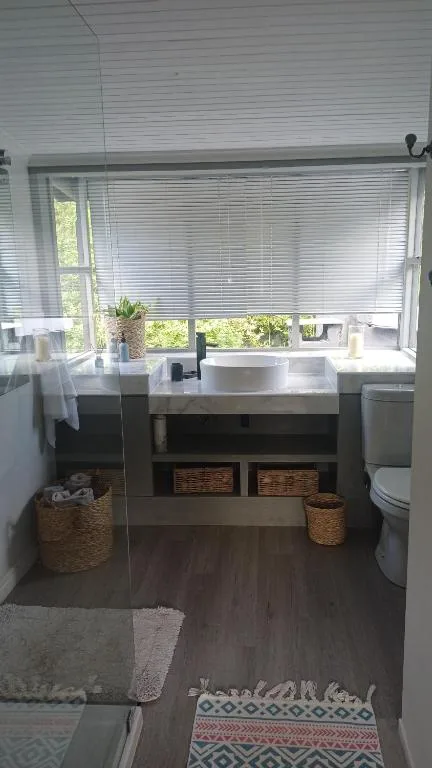 Modern bathroom with white vessel sink, dark vanity, and woven storage baskets