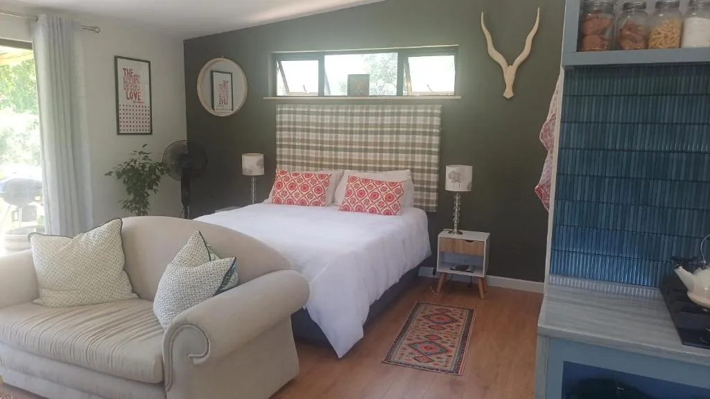 Bedroom with queen bed, green accent wall, and comfortable seating area