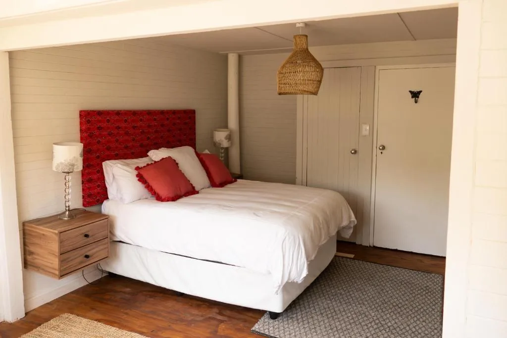 Spacious bedroom with queen bed, red headboard, and wooden nightstand lamp