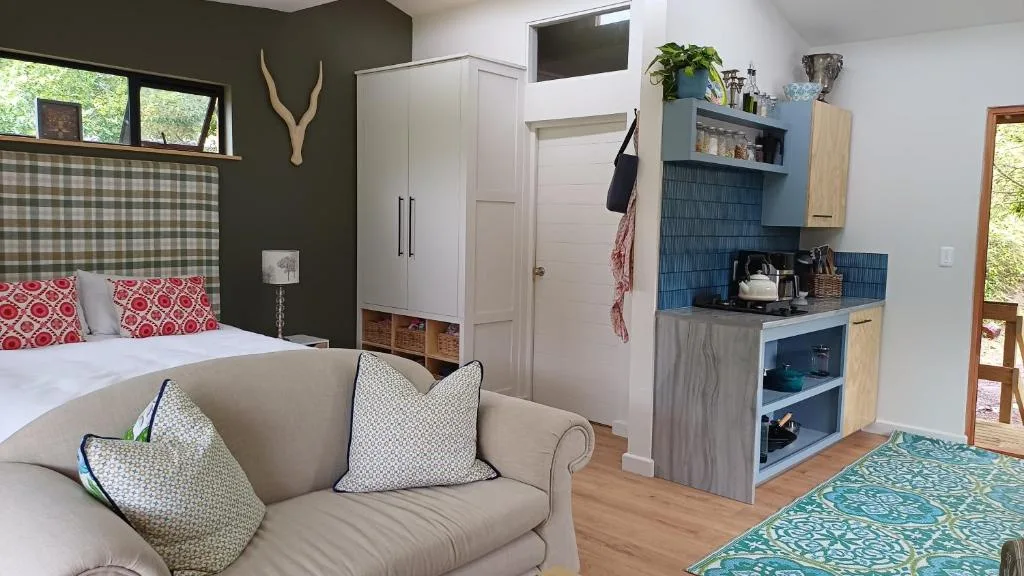 Cozy bedroom with bed, seating area, kitchenette, and dark accent wall