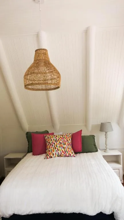 Bright bedroom with woven pendant light and colorful accent pillows