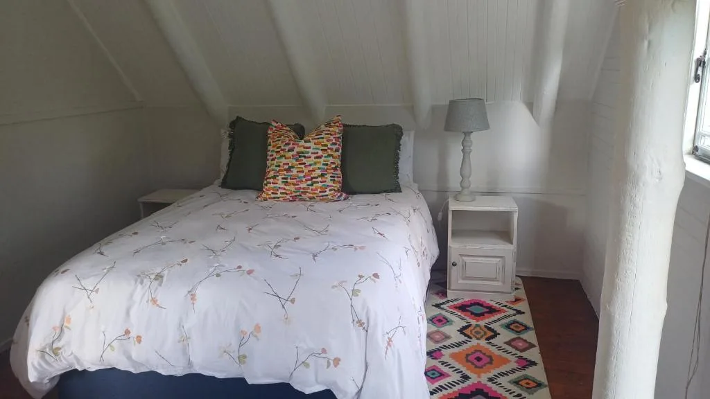 Cozy bedroom with floral bedding, colorful cushions, and bedside lamp